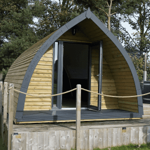 Timber glamping pod surrounded by grass and trees