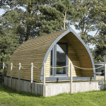 Timber glamping pod surrounded by grass and trees