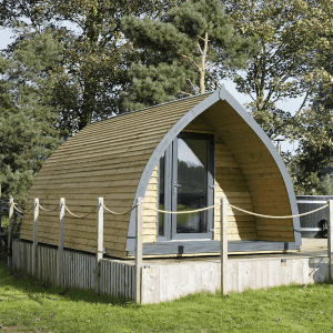 Timber glamping pod surrounded by grass and trees