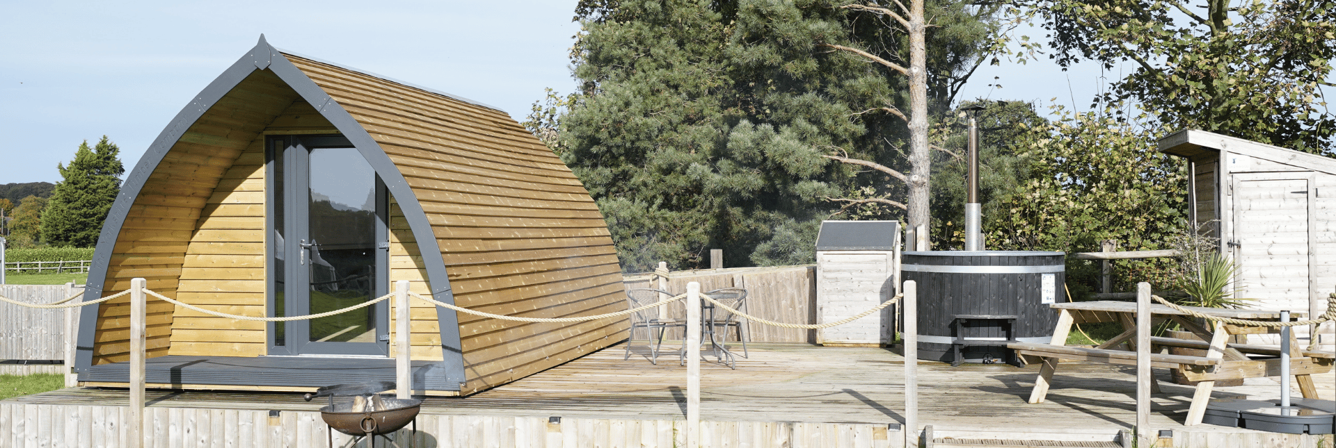 Timber pod on decking with a hot tub and shed