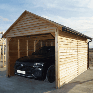 Timber garage housing a black car