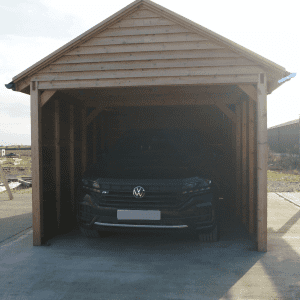 Timber garage housing a black car