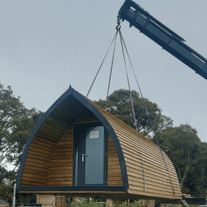 Timber glamping pod being lifted into place by a crane